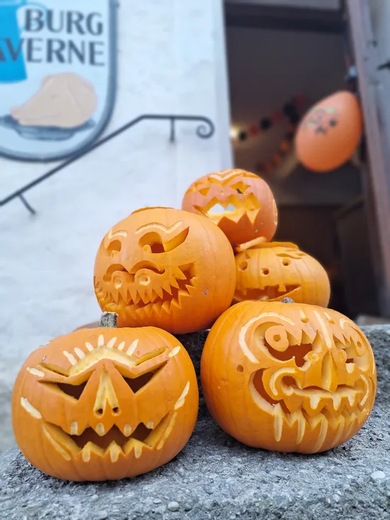 Group of carved Halloween pumpkins with spooky faces on stone steps