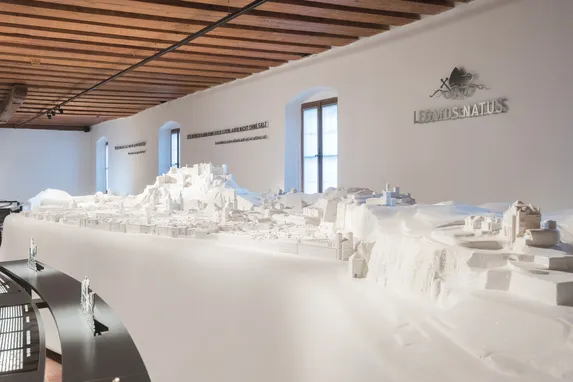 Modello urbano 3D bianco dettagliato esposto in un museo con soffitto in legno ed espositori curvi
