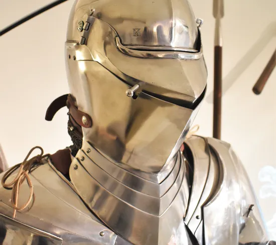 Mittelalterliche Ritterrüstung mit geschlossenem Helm und polierter Metalloberfläche ausgestellt