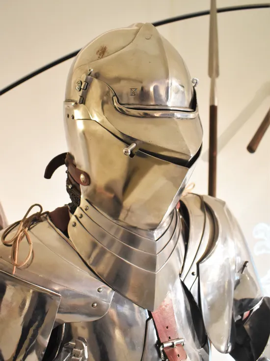 Mittelalterliche Ritterrüstung mit geschlossenem Helm und polierter Metalloberfläche ausgestellt