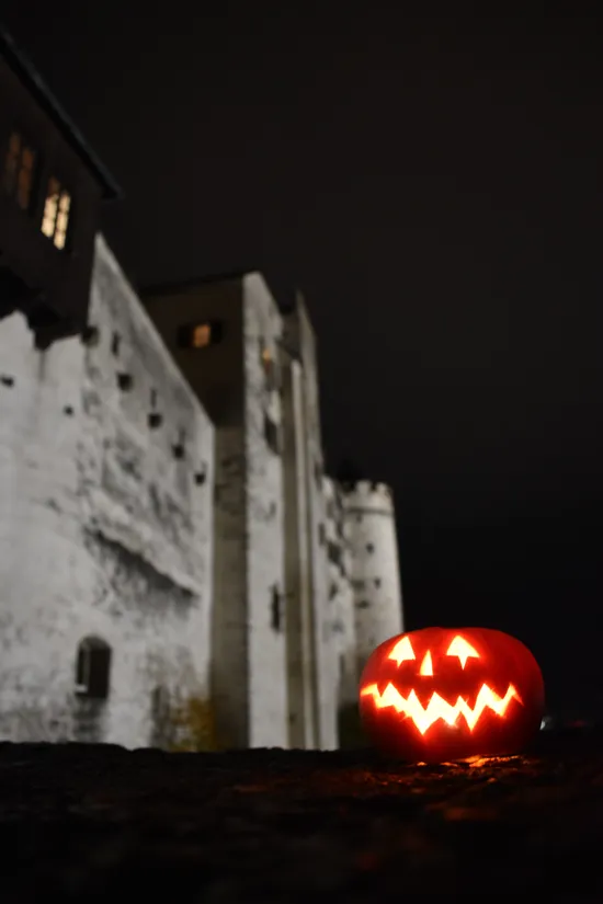 Lanterna di Halloween illuminata su muro di pietra davanti a castello medievale di notte
