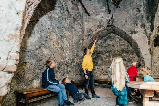 Fremdenführer zeigt Kindern ein mittelalterliches Gewölbe in einem historischen Gebäude