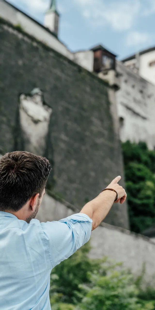 Mann zeigt auf Festung Hohensalzburg