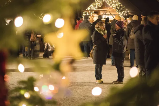 Couple talking at Christmas market with festive lights and blurred tree decorations