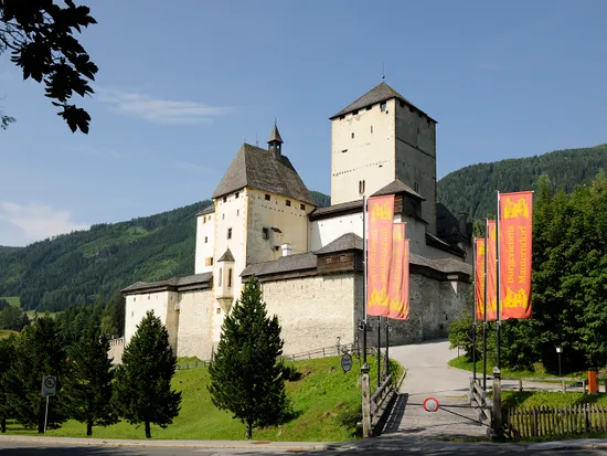 Burg Mauterndorf mit mittelalterlichen Türmen und bunten Fahnen in den österreichischen Alpen