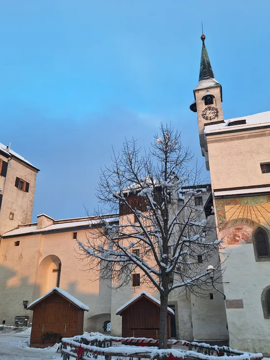 Snow-covered church and historic buildings with sundial and wooden stalls in winter