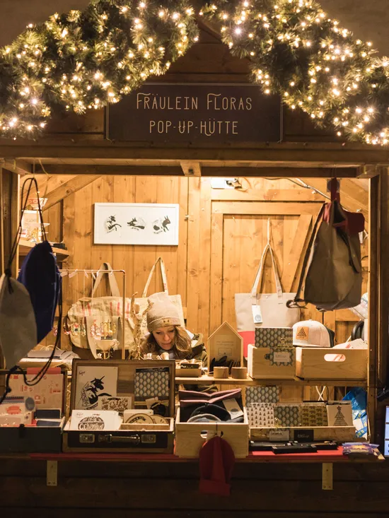 Christmas market stall with handmade gifts, tote bags and festive lights in Salzburg