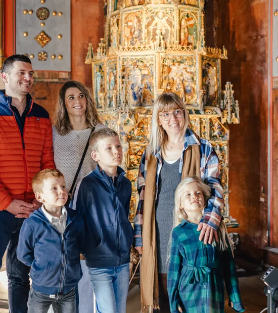 Gruppe mit Kindern hört einem Guide in einem prunkvollen historischen Gebäude zu