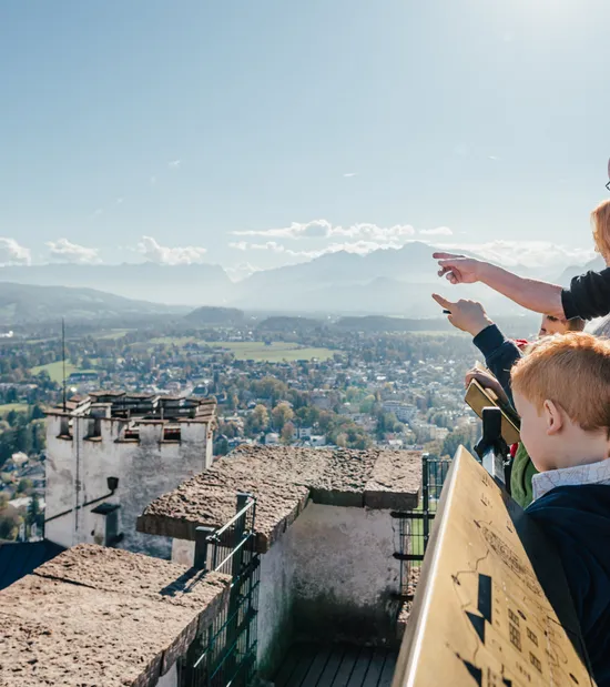 Famiglia osserva il panorama di Salisburgo dal punto panoramico della Fortezza di Hohensalzburg in una giornata di sole