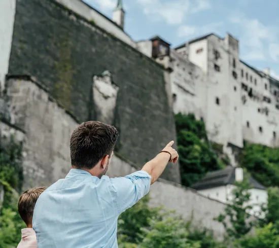 Mann zeigt auf Festung Hohensalzburg
