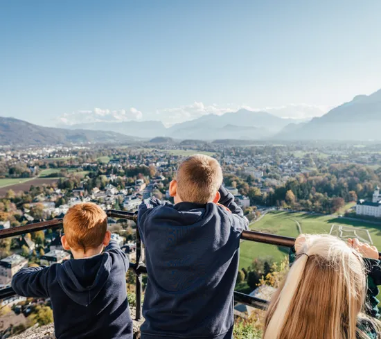 Bambini guardano il paesaggio urbano e montano da un punto panoramico elevato