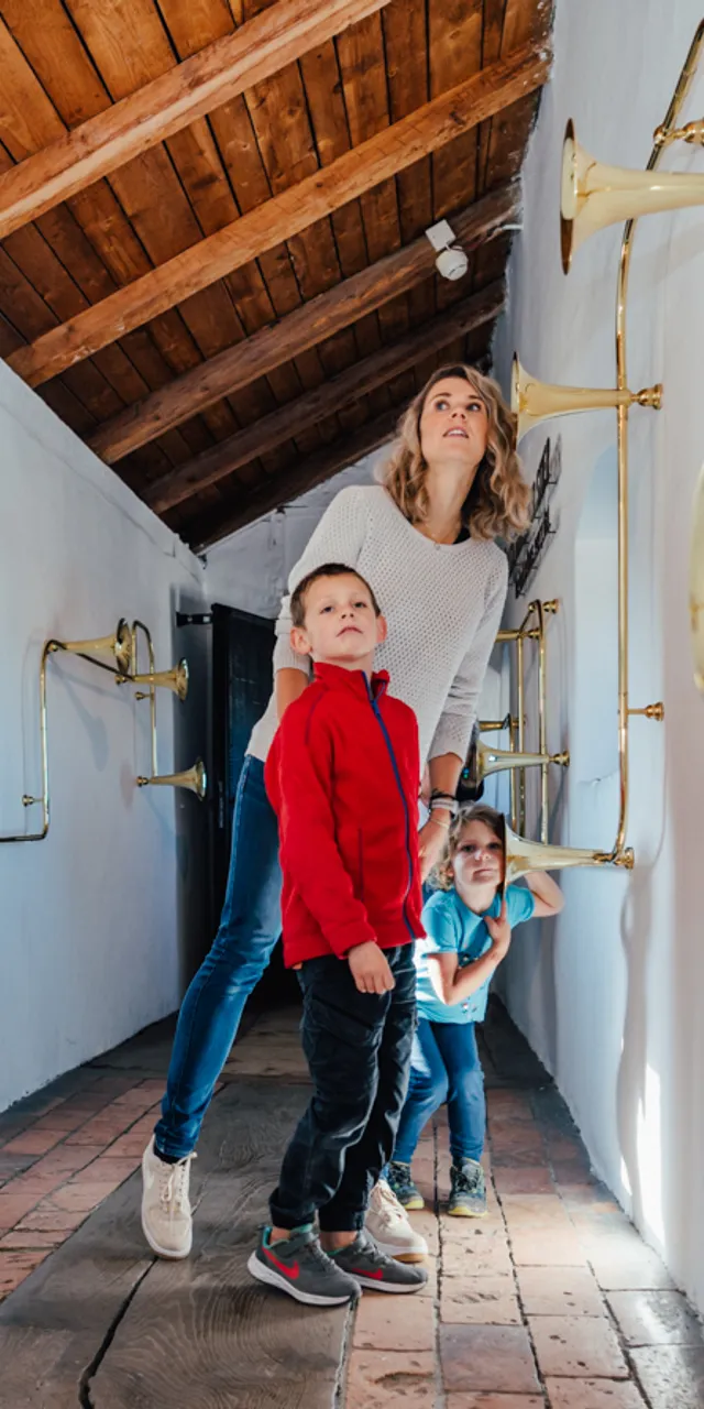 Familie erkundet Klangtunnel mit Messinghörnern an den Wänden im interaktiven Wissenschaftsmuseum