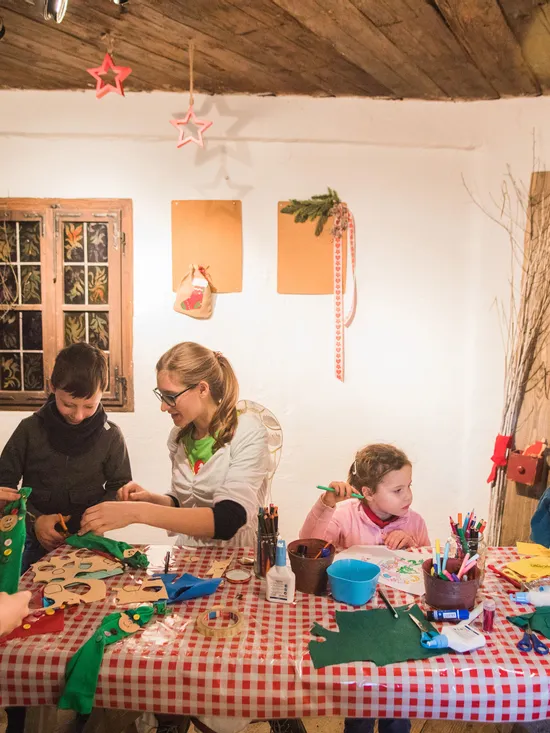 Children crafting Christmas decorations at a table with festive supplies