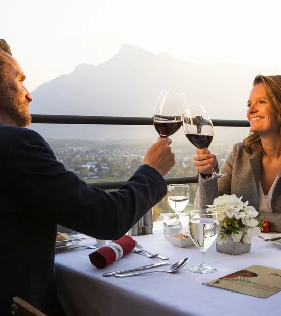 Couple toasting with red wine at romantic outdoor dinner with mountain view