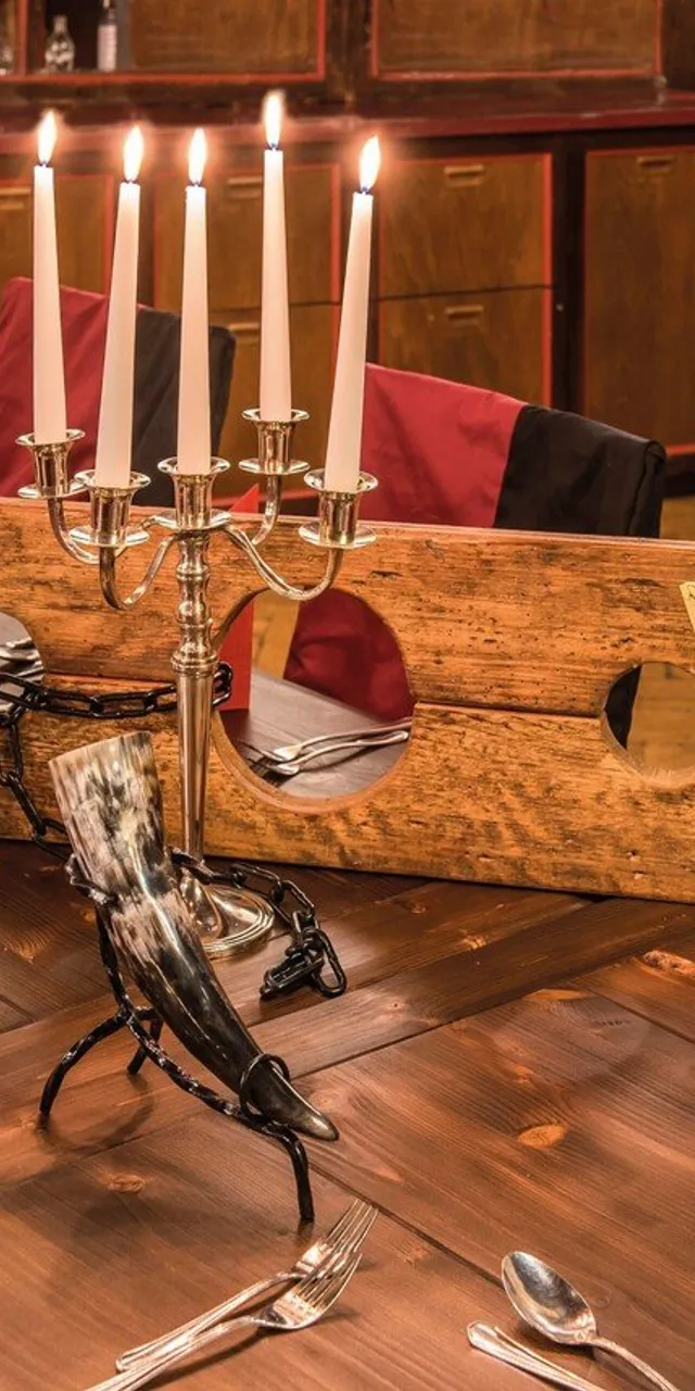Rustic dining table with candles, wine bottles, and parchment rolls