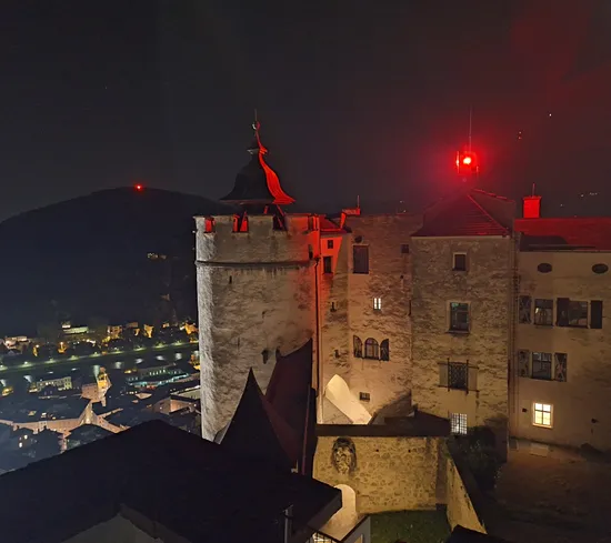 Mittelalterlicher Burghof bei Nacht in Salzburg von roten Lichtern beleuchtet