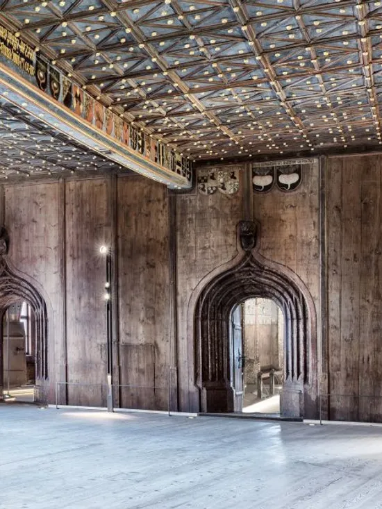 Historischer Saal mit gedrehten Steinsäulen, Holzvertäfelung und kunstvoller Decke im Schlossinneren
