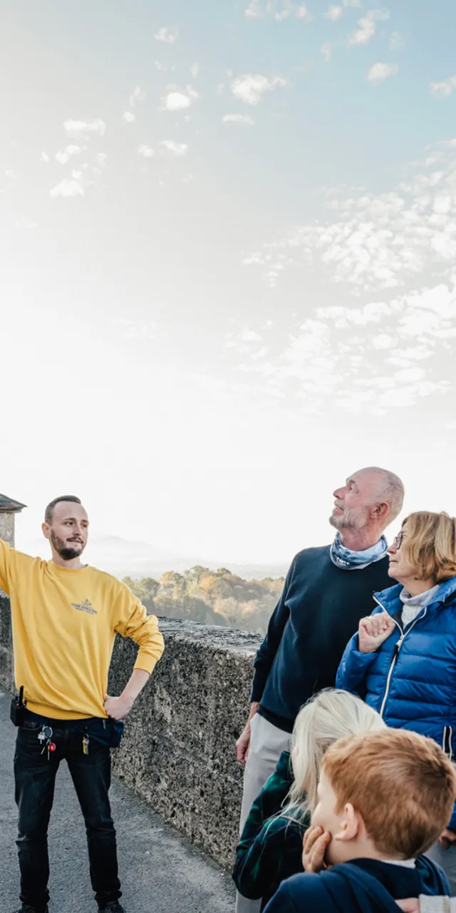 Guida turistica spiega la storica Fortezza di Salisburgo a un gruppo di visitatori all'aperto