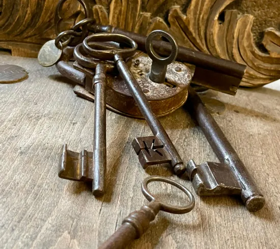 Rostige antike Metallschlüssel und Vorhängeschloss auf Holztisch mit geschnitztem Hintergrund