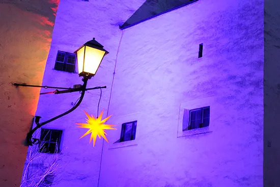 Historic building facade lit with purple lighting and yellow star lantern at dusk