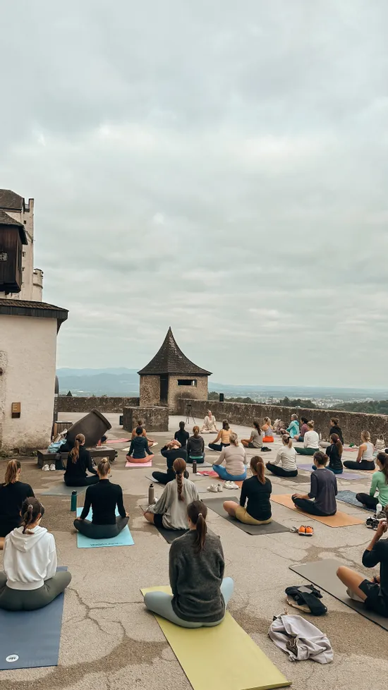 Sessione di yoga di gruppo all'aperto su una terrazza del castello con vista sulle montagne