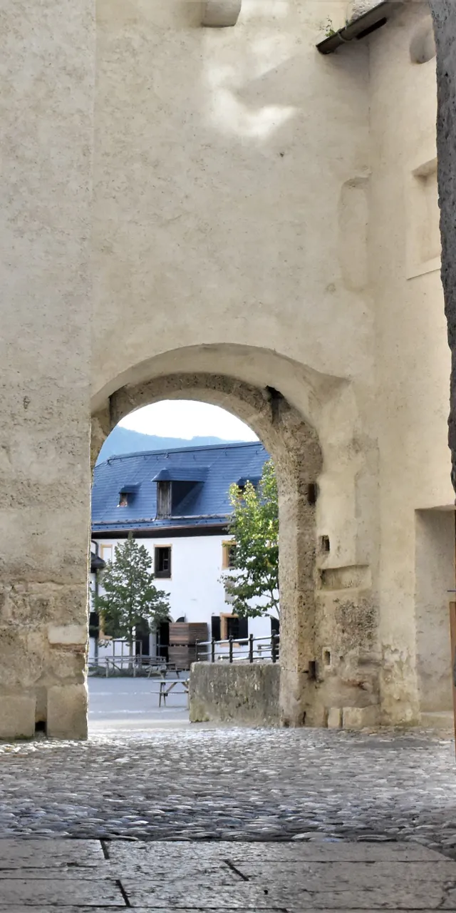 Steinbogen mit Laterne führt zu einem Kopfsteinpflasterhof und historischen Gebäuden