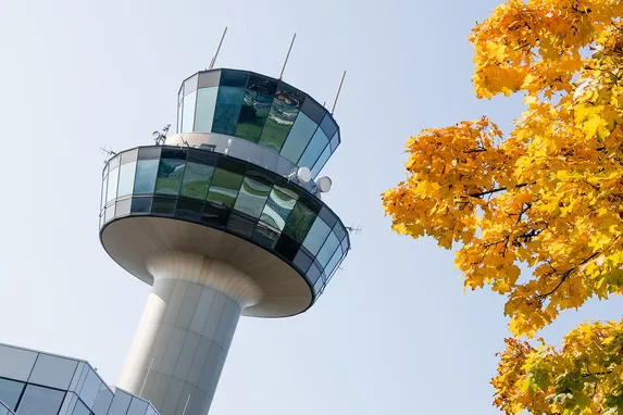 Moderna torre di controllo aeroportuale accanto ad albero autunnale con foglie gialle