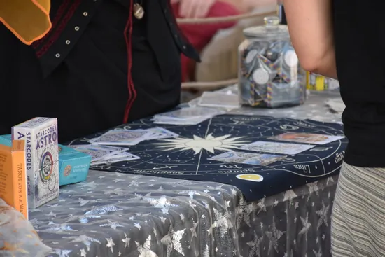 Tarot-Lesung mit Sternzeichen-Tuch, Orakelkarten und Tarotkartensets an einem Marktstand