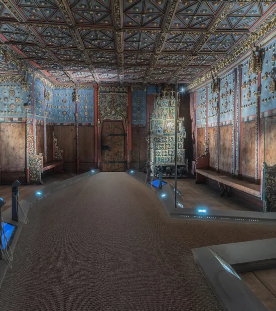 Ornate wooden room with painted ceiling and walls, showcasing historical Eastern European interior design