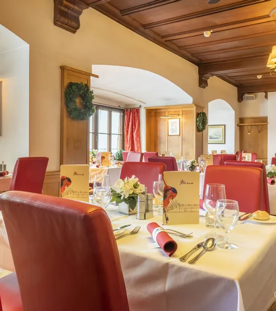 Elegant restaurant dining room with red chairs, white tablecloths, and floral centerpieces