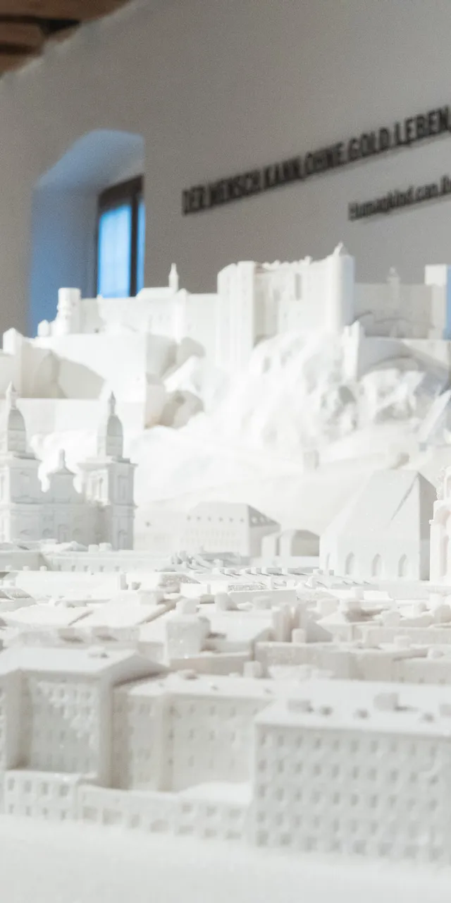 Detailed white model of Salzburg with buildings and Hohensalzburg Fortress in a museum exhibit