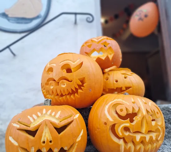 Gruppe geschnitzter Halloween-Kürbisse mit gruseligen Gesichtern auf Steintreppen