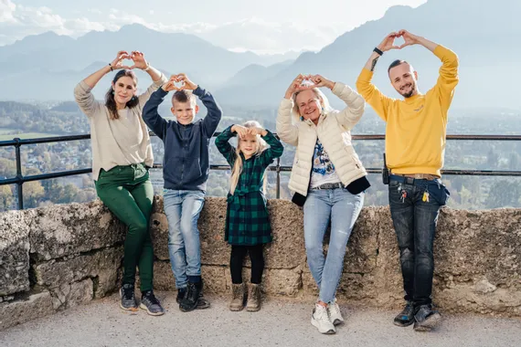 Smiling family making heart shapes with hands at scenic mountain viewpoint