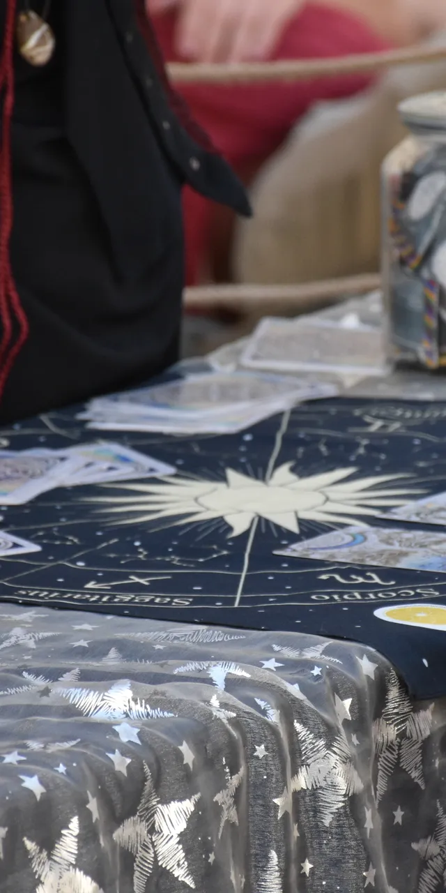 Tarot-Lesung mit Sternzeichen-Tuch, Orakelkarten und Tarotkartensets an einem Marktstand