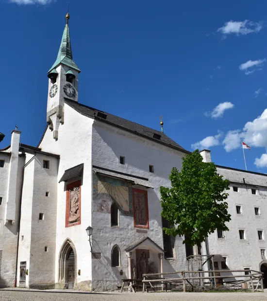 Historische weiße Festung mit Uhrturm und Wandfresken unter blauem Himmel