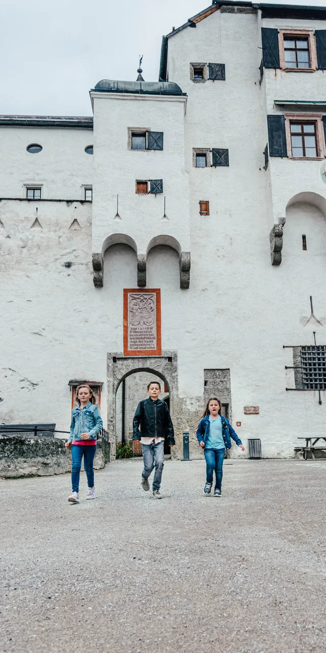 Kinder erkunden den Innenhof der Festung Hohensalzburg in Salzburg, Österreich