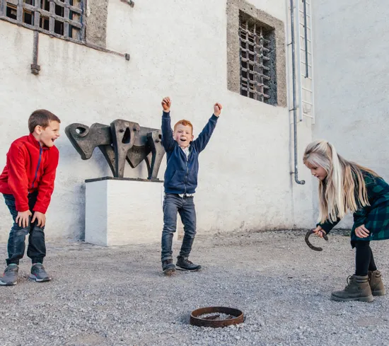 Bambini giocano al lancio dell'anello nel cortile vicino a scultura astratta in metallo