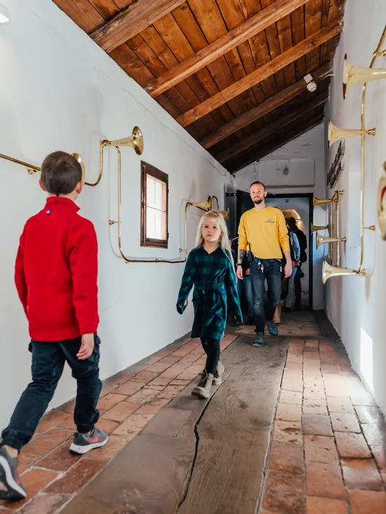 Familie geht durch Museumsgang mit Messinginstrumenten an weißen Wänden
