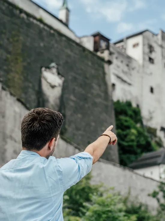 Mann und Kind zeigen auf eine historische Festung auf einem Hügel