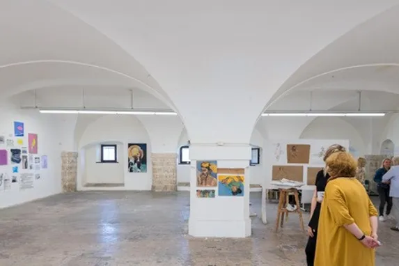 Kunstausstellung in einem gewölbten Galerieraum mit Besuchern, die Gemälde betrachten