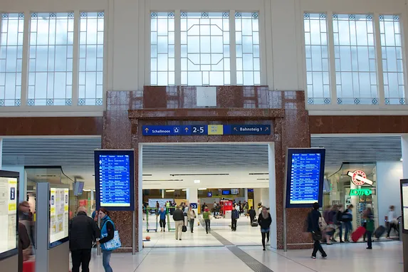 Sala principale della stazione ferroviaria di Salisburgo con viaggiatori e tabelloni elettronici