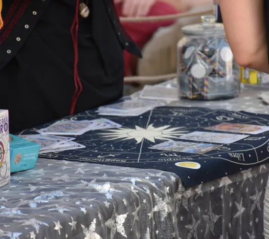 Tarot-Lesung mit Sternzeichen-Tuch, Orakelkarten und Tarotkartensets an einem Marktstand