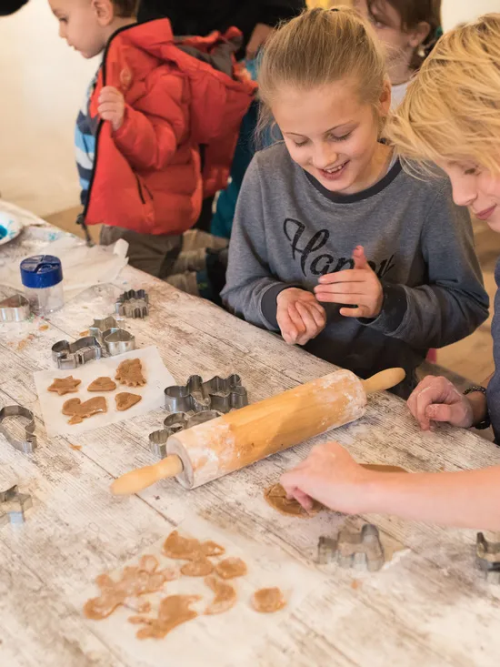Children using cookie cutters to shape gingerbread dough at a messy baking table