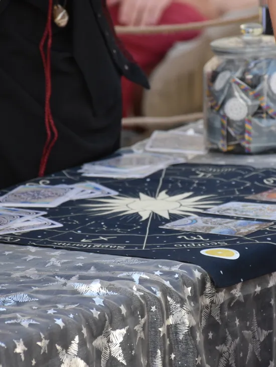 Tarot-Lesung mit Sternzeichen-Tuch, Orakelkarten und Tarotkartensets an einem Marktstand