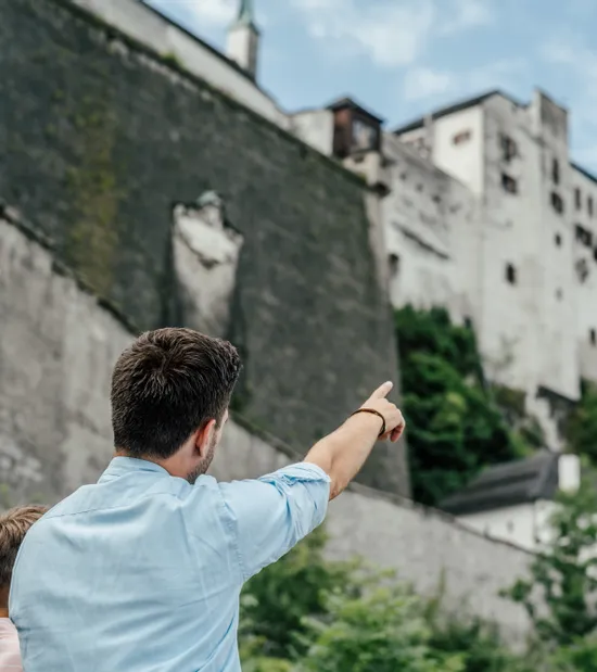 Mann zeigt auf Festung Hohensalzburg