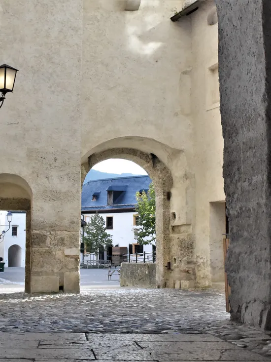Steinbogen mit Laterne führt zu einem Kopfsteinpflasterhof und historischen Gebäuden