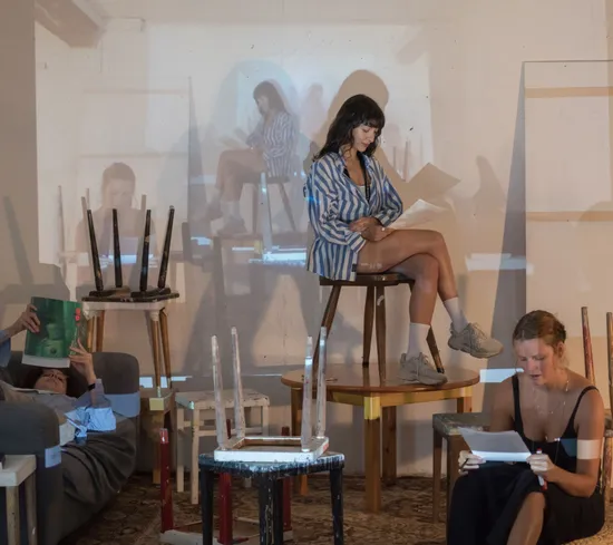 Drei Personen lesen in einem Atelier mit projizierten Bildern an der Wand