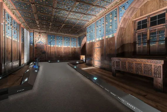 Historischer Holzraum mit blauer Wandverkleidung, verziertem Deckengewölbe und geschnitzter Truhe